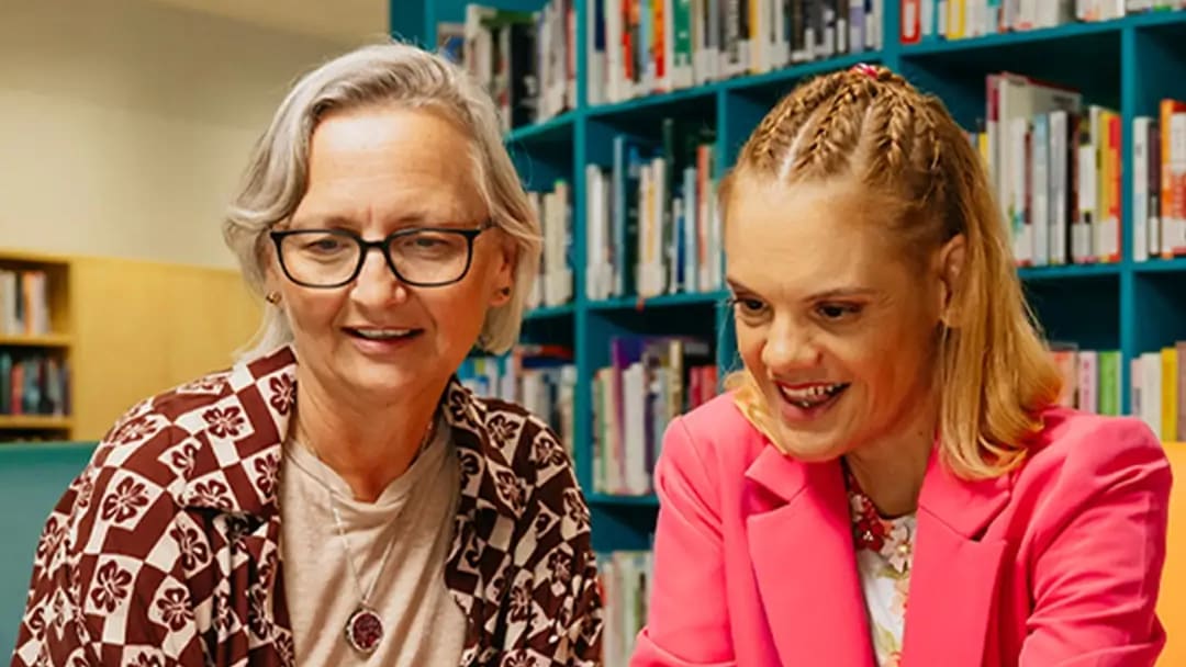 Support coordinator and their client with disability sit at a laptop to search for support workers.