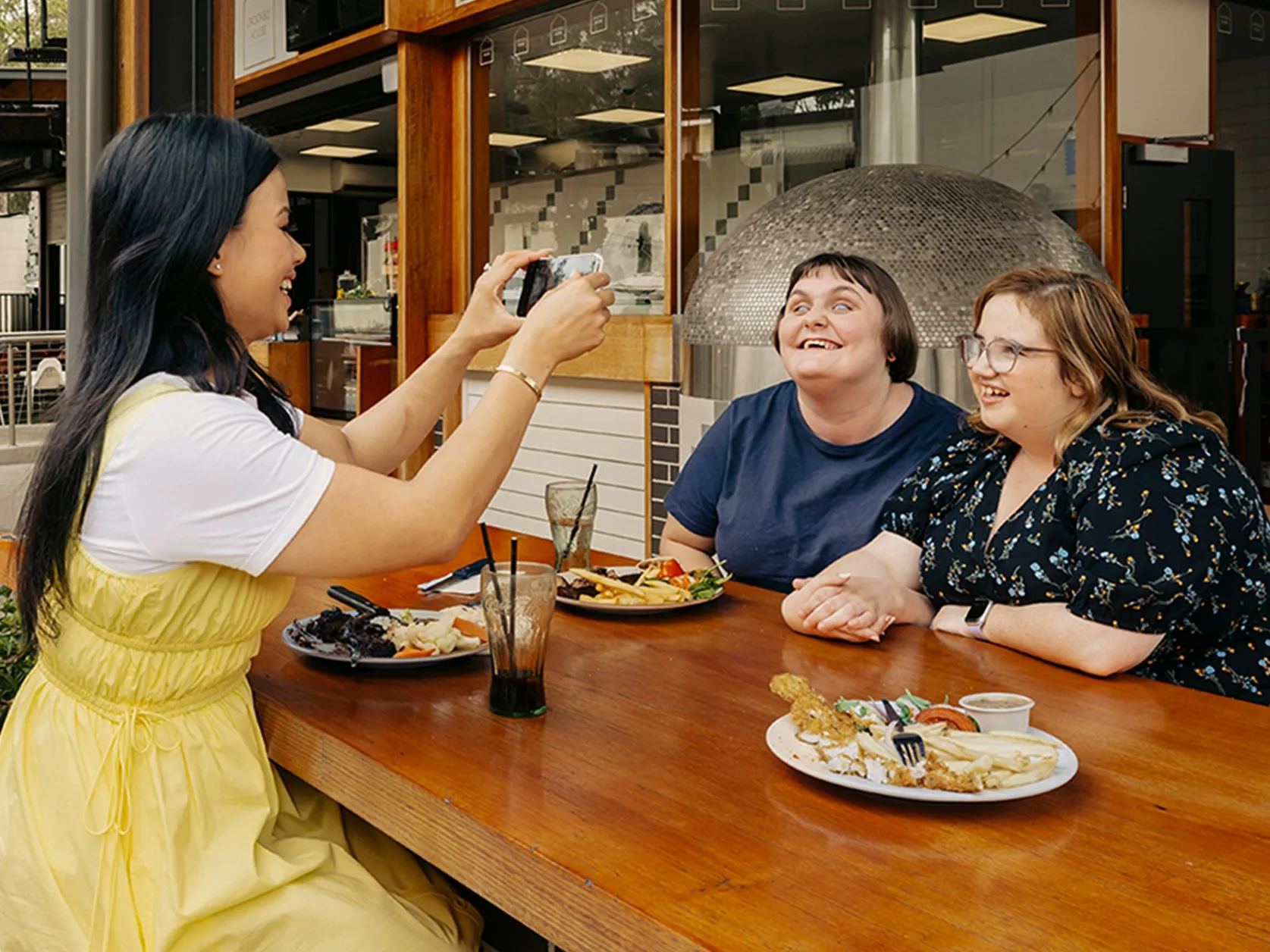 Couple with disability eating at pub pose for a photo their support worker is taking.