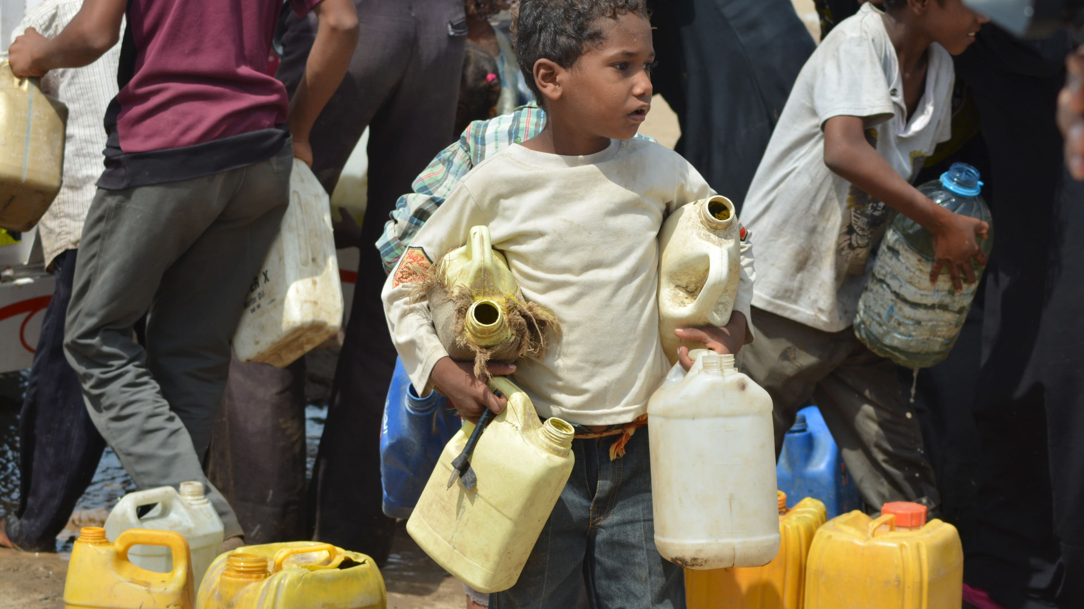 Boy carries jerry cans to fill from a water tanker truck in a slum neighborhood in Yemen's Red Sea city of Houdieda
