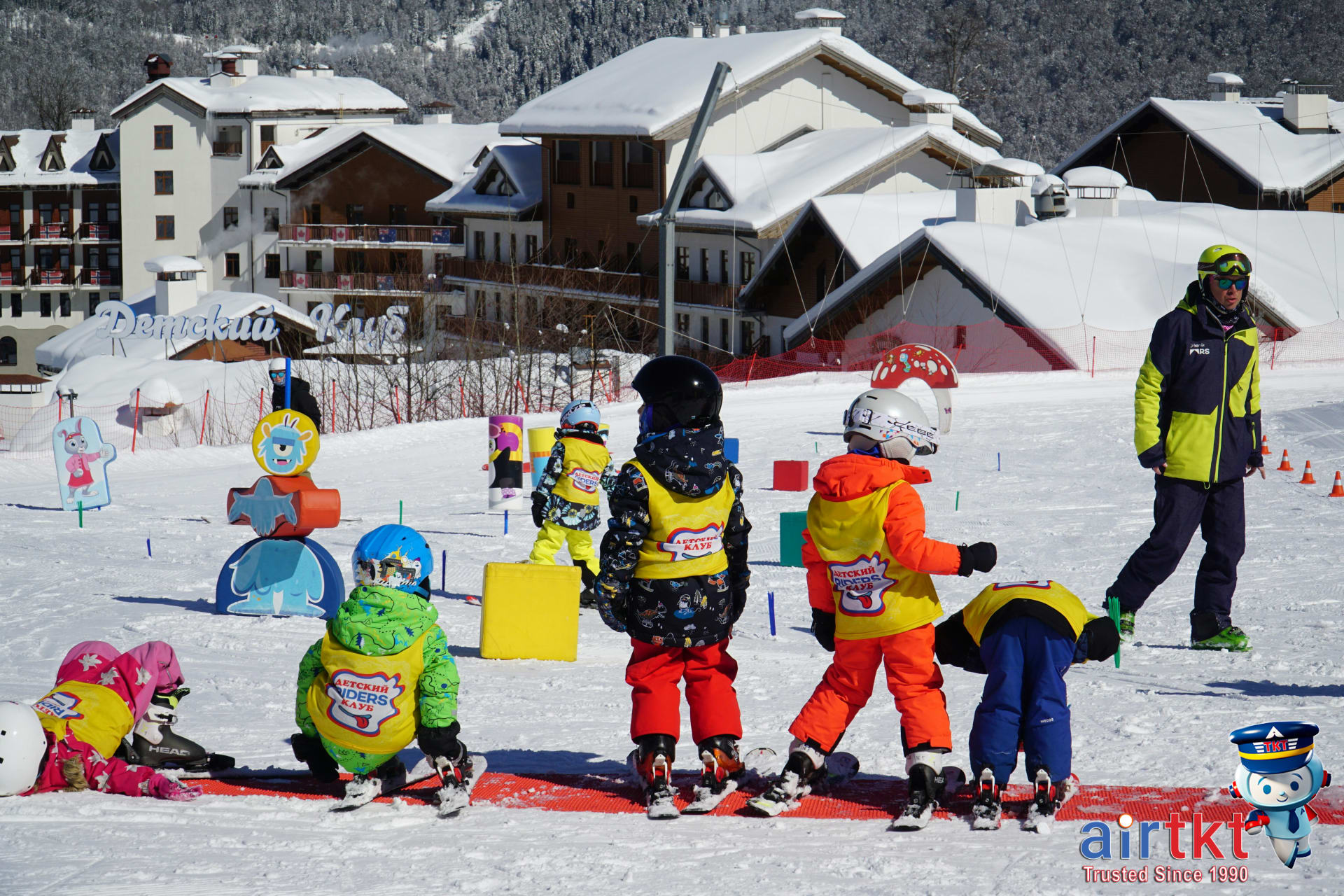 Children enjoying ski lessons on a snowy slope with helpful instructor in the Alps