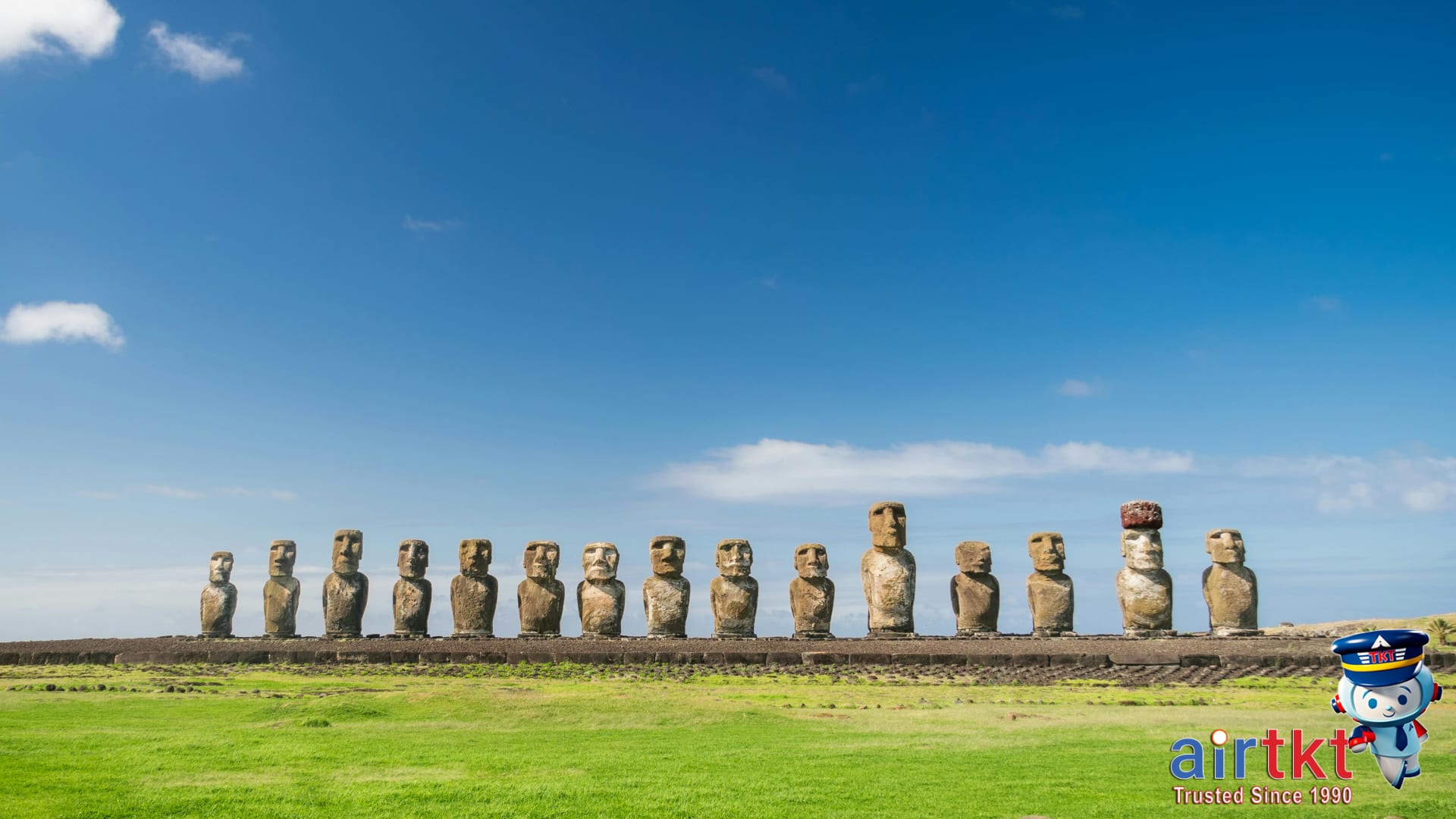 Tourists visiting Ahu Tongariki Moai statues on Easter Island with ocean in background