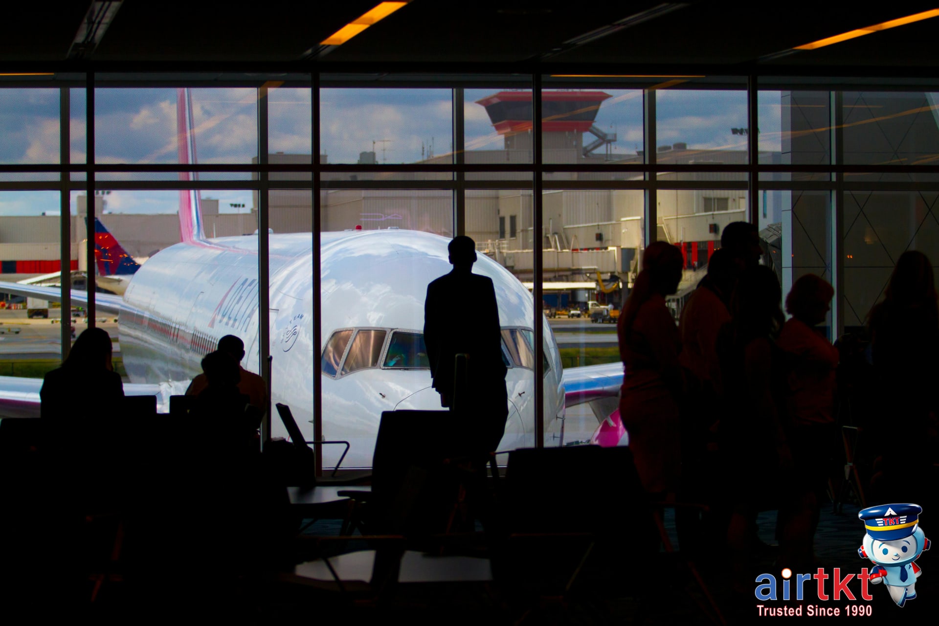 Silhouettes of travelers at airport with airplane through window in April spring break
