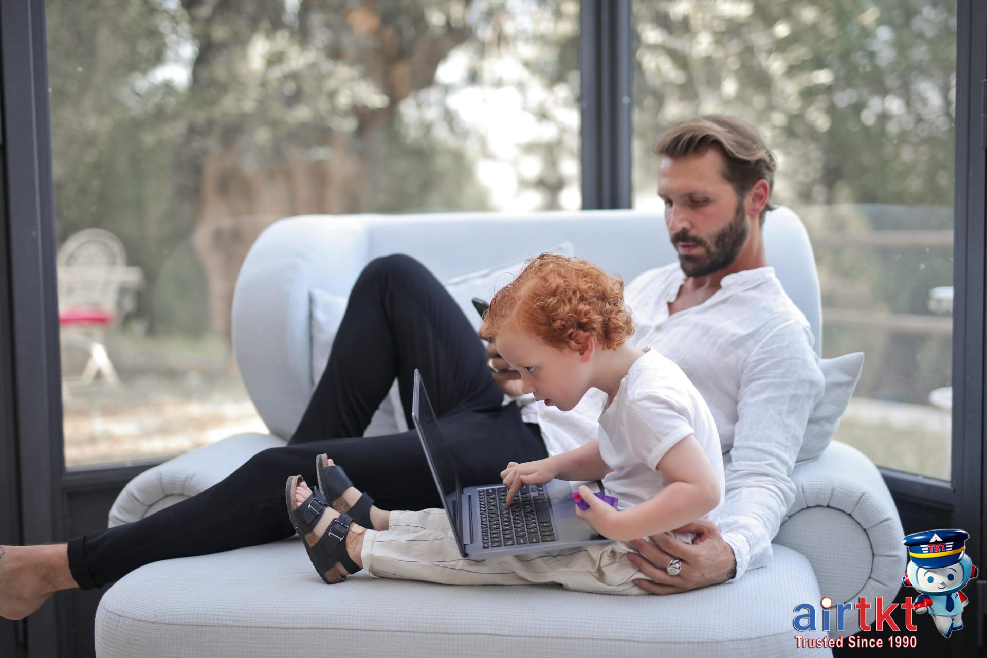 Father and young son using laptop and phone booking travel deals in April