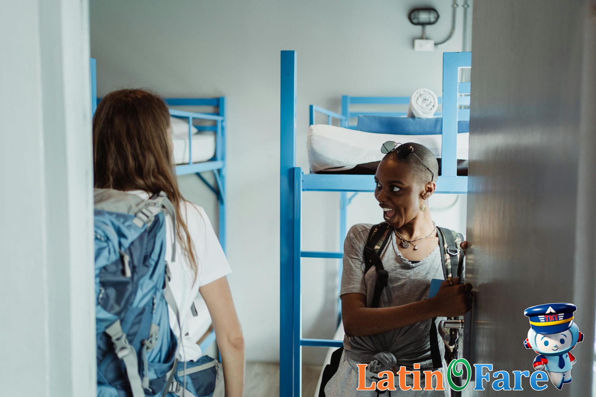 Two women with backpacks walking into a bright South American hostel dorm with bunk beds on the Gringo Trail