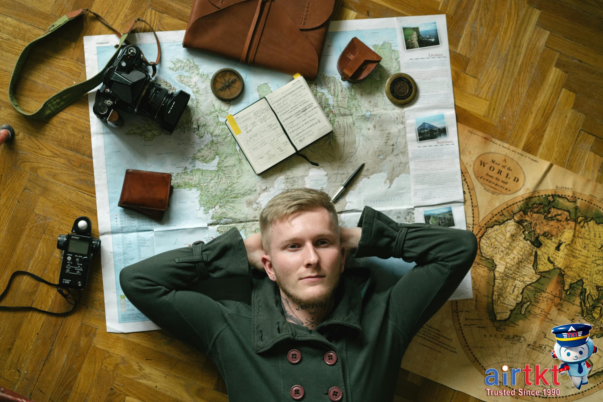 Travelers sitting at table with maps, receipts, and a smartphone planning their travel budget