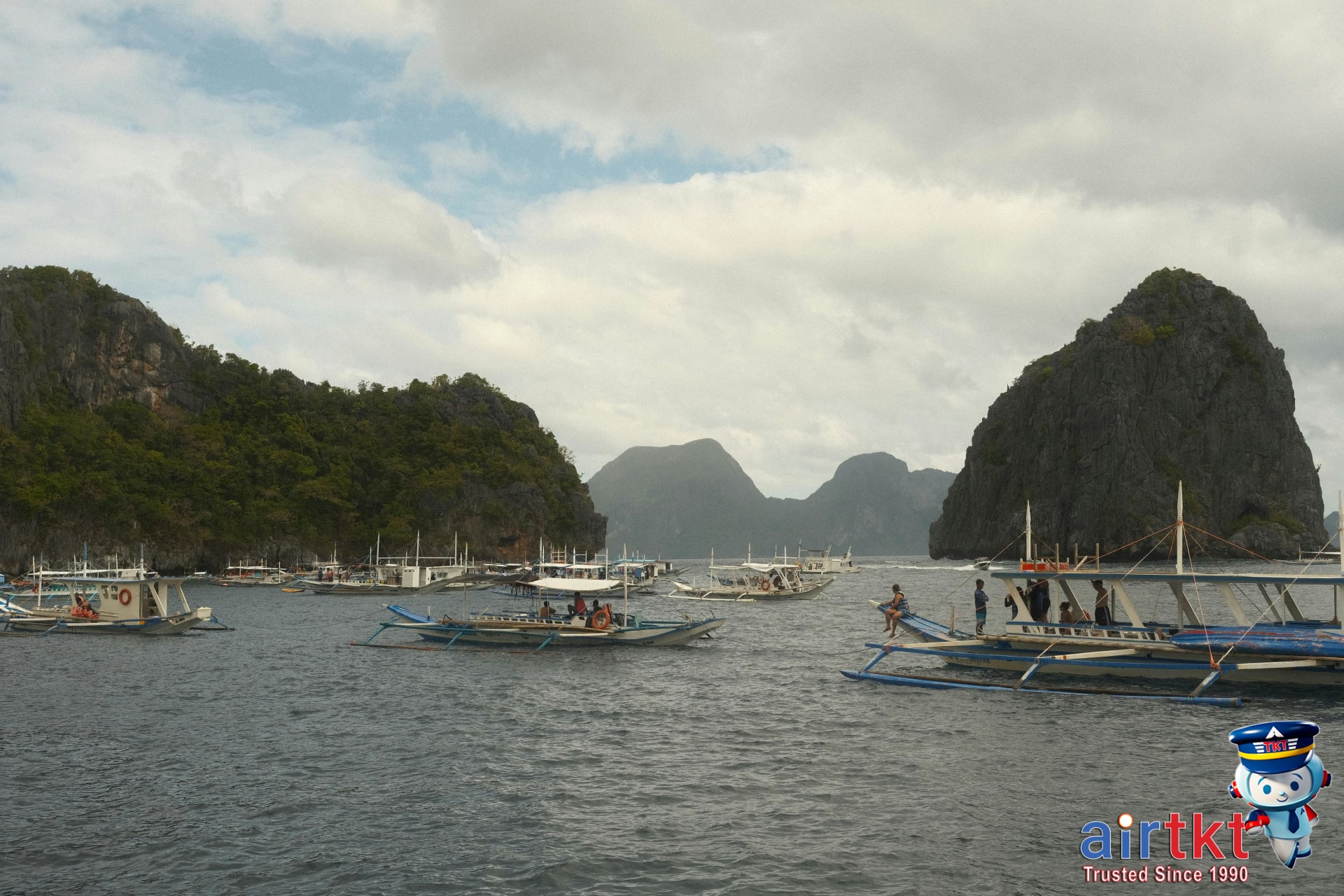 Traditional boats moored for island hopping tours near limestone cliffs in the Philippines