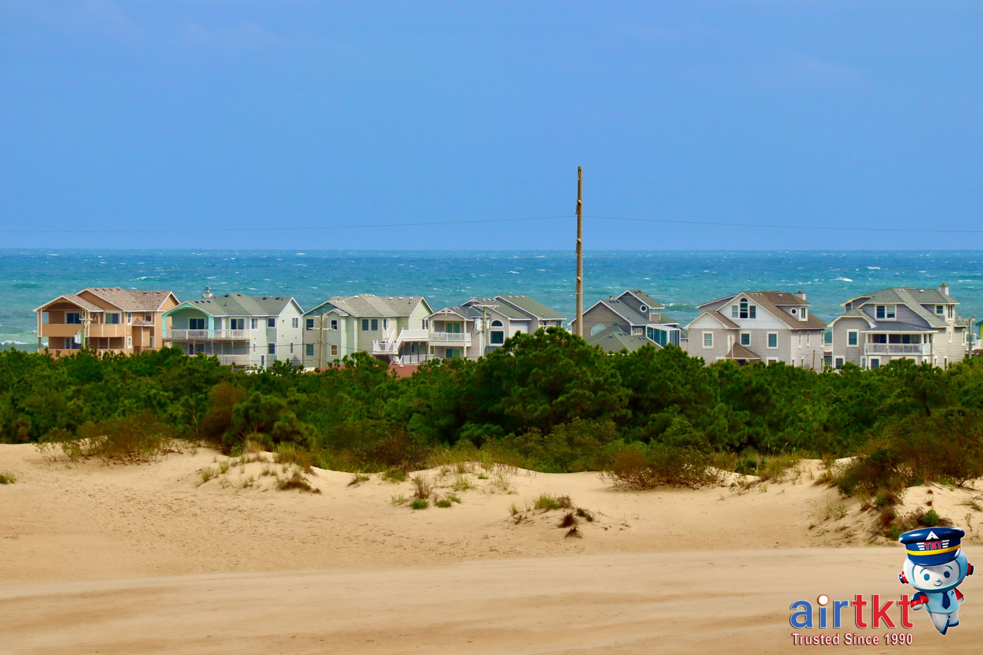 Colorful beach houses on Outer Banks with wooden paths, illustrating local accommodations