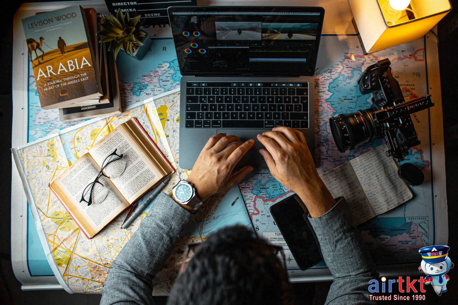 Man planning travel itinerary using laptop and maps for Latin America flights