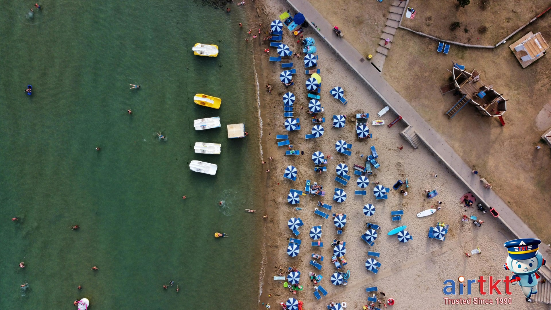 Aerial view of popular July beach with clear water and families enjoying shore
