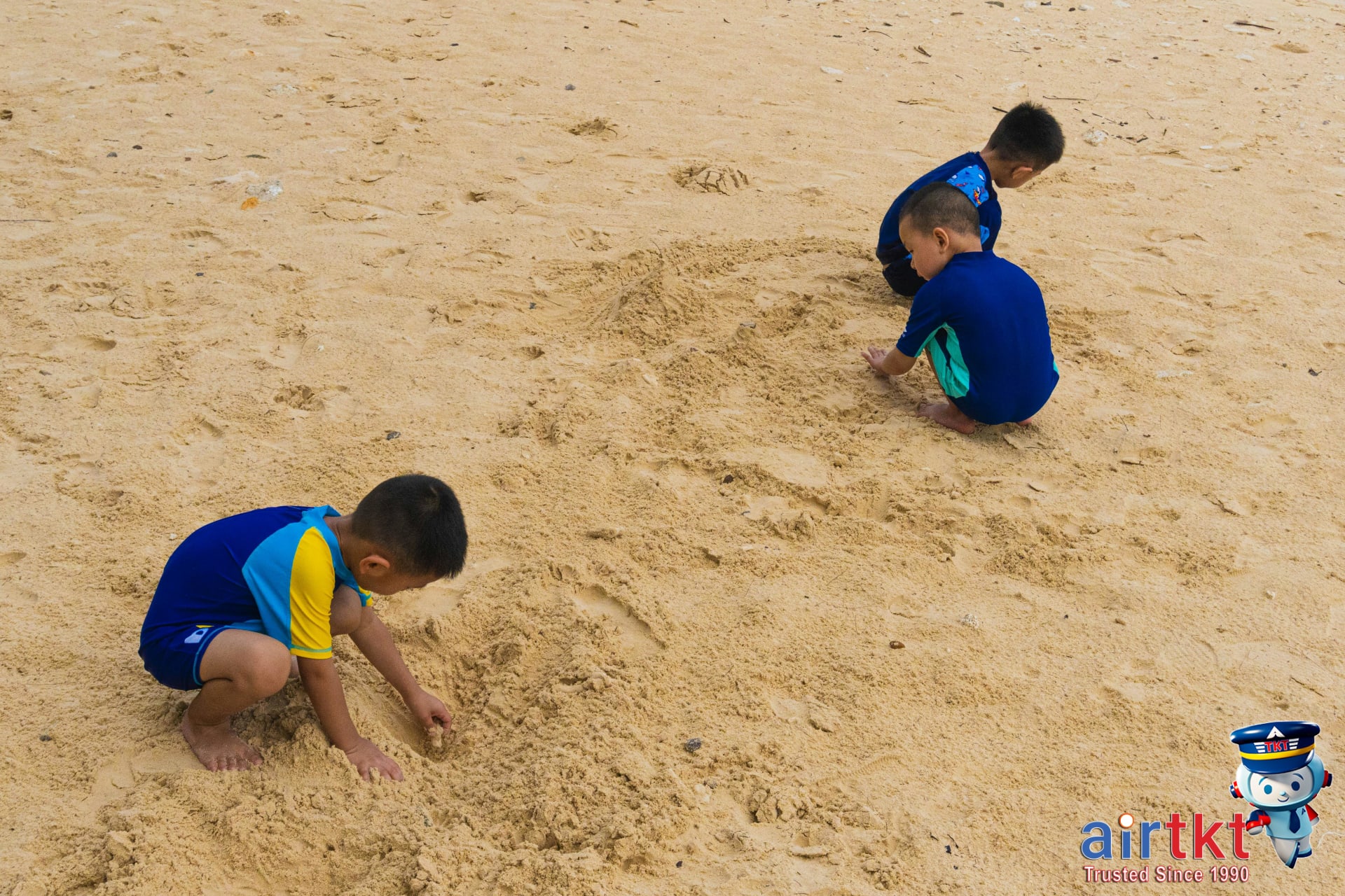 Children building sandcastles and families playing beach games in July on a sunny coast