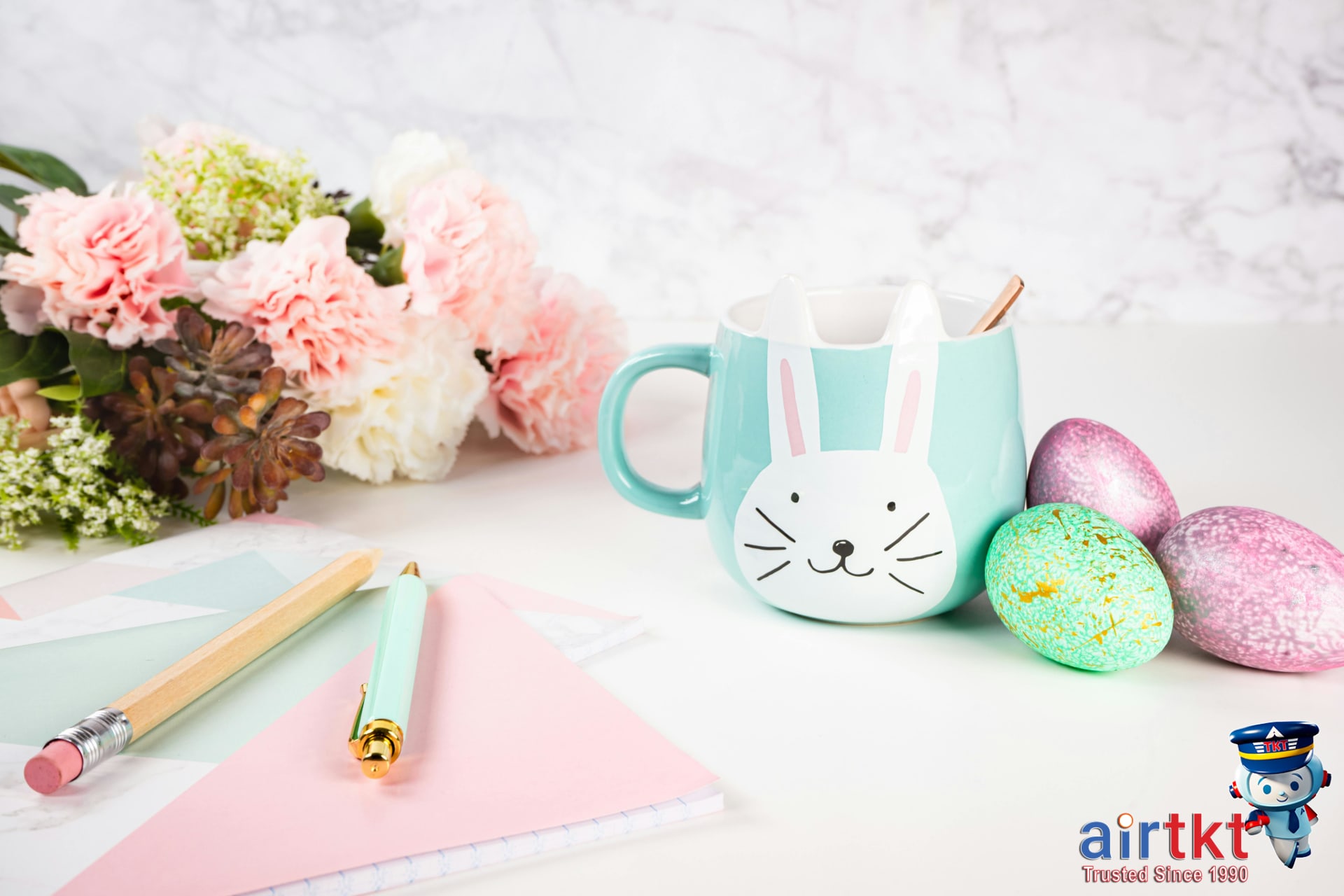 Booking Easter travel online with spring flowers and pastel decorations nearby