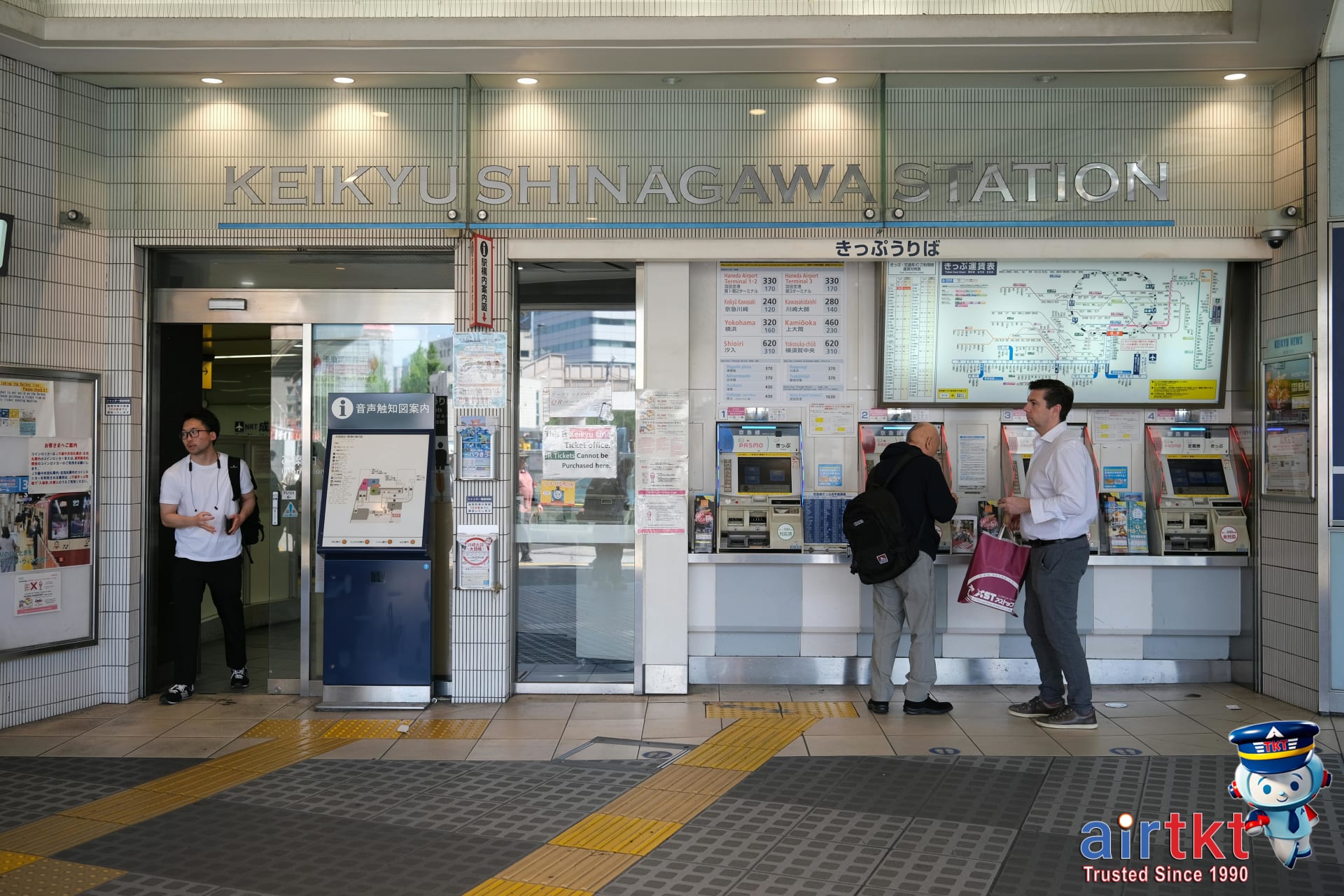Travelers comparing Japan Rail Pass and regular train ticket prices at a ticket counter
