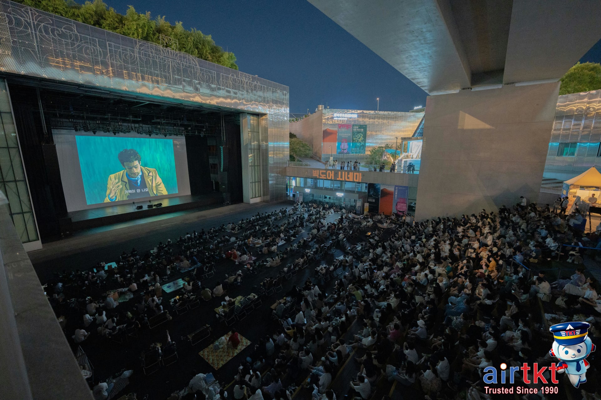 Film screening event outdoors at night with audience gathered