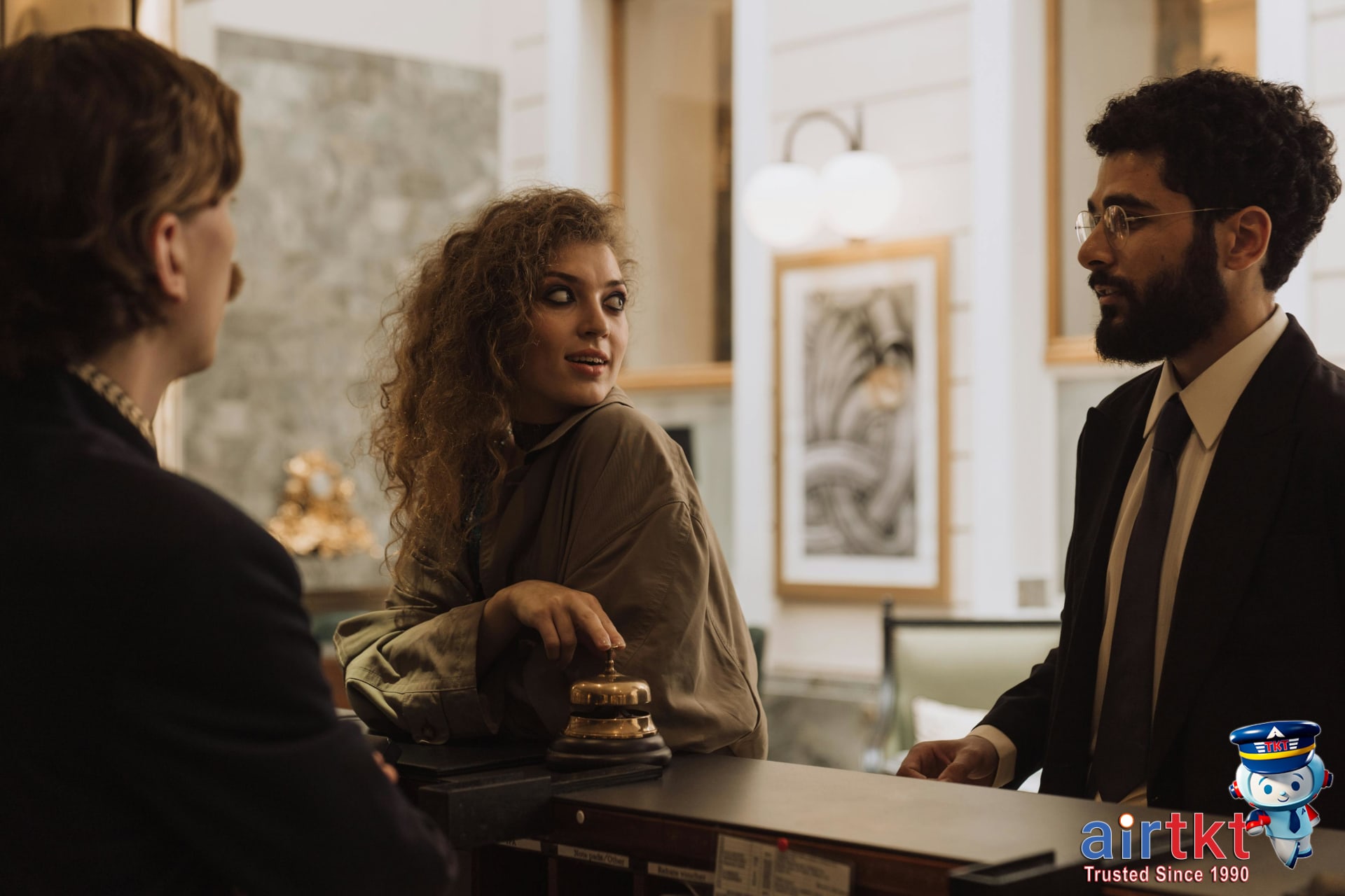 Guests at luxurious hotel reception desk discussing flexible rate options with staff