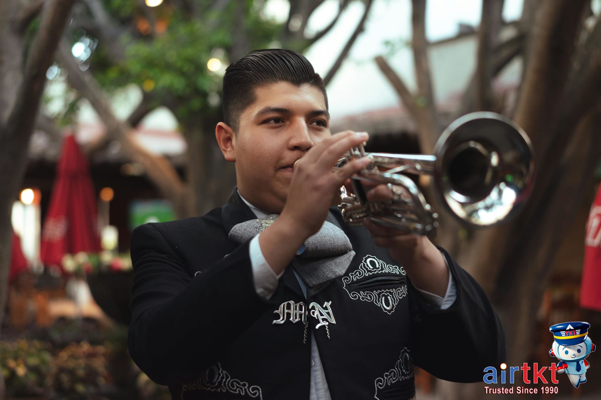 Mariachi musician playing trumpet outdoors in traditional Mexican attire in Guadalajara
