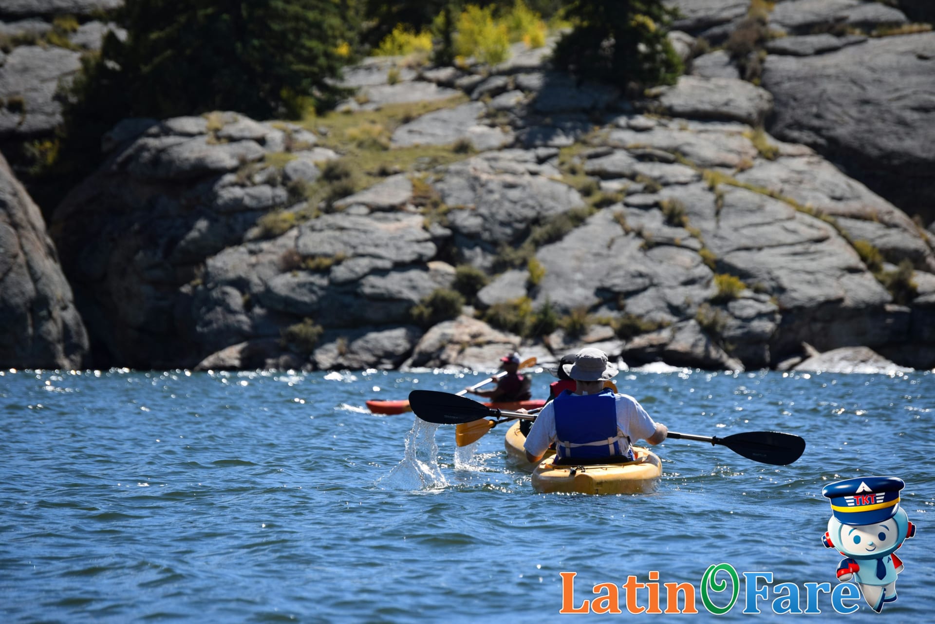 Summer adventure travelers kayaking on scenic mountain lake during early June outdoor vacation.