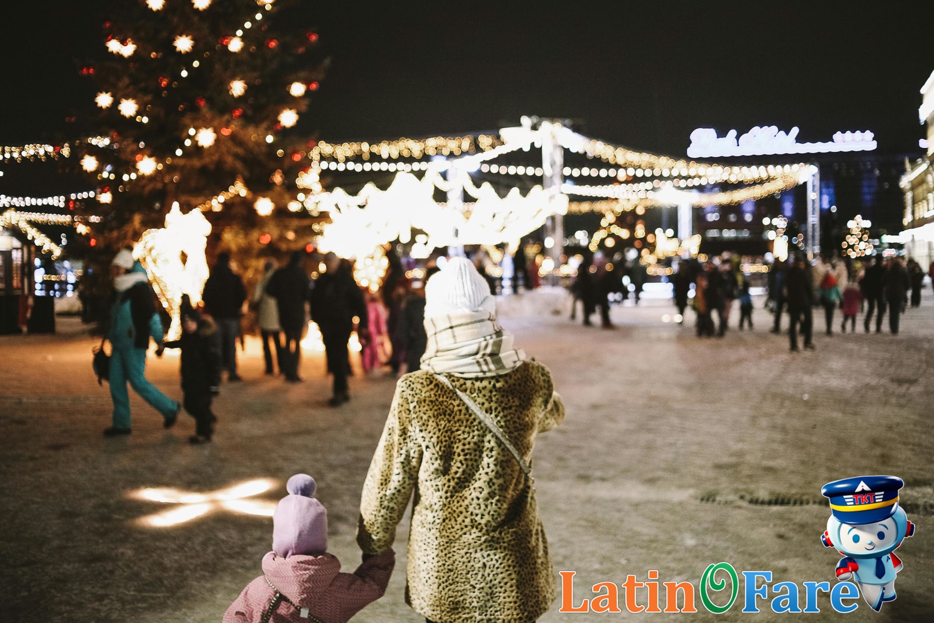 Family enjoying Christmas travel at a festive holiday market night with twinkling lights