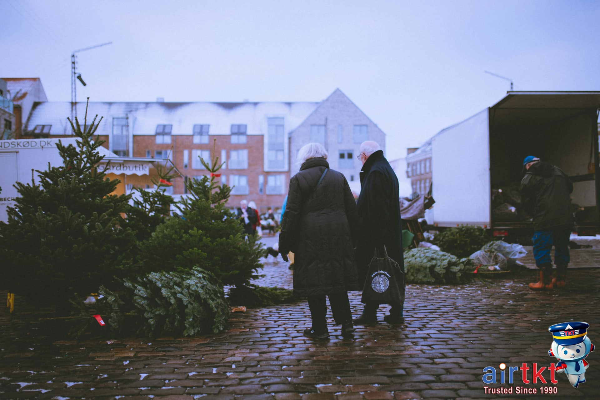 Elderly couple enjoying festive outdoor Christmas market with holiday decorations