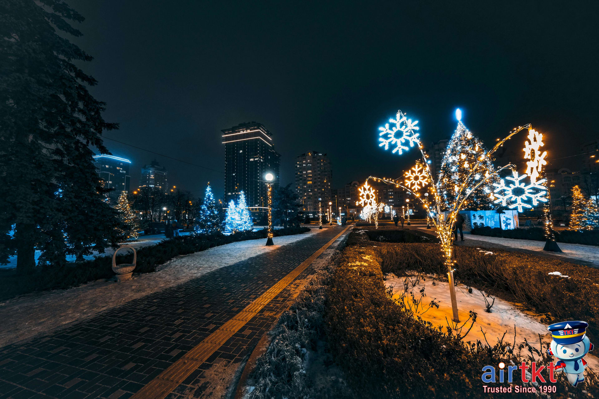 Holiday lights illuminating city streets and festive landmarks at night