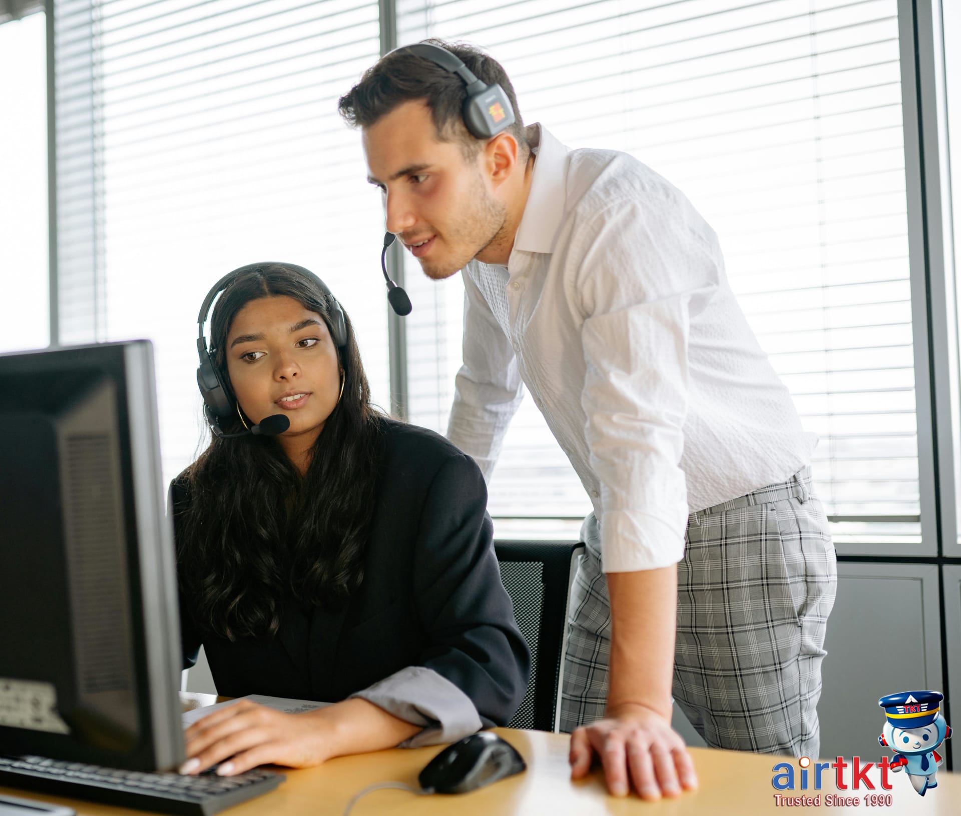 Travel agent assisting customer with flight booking on computer