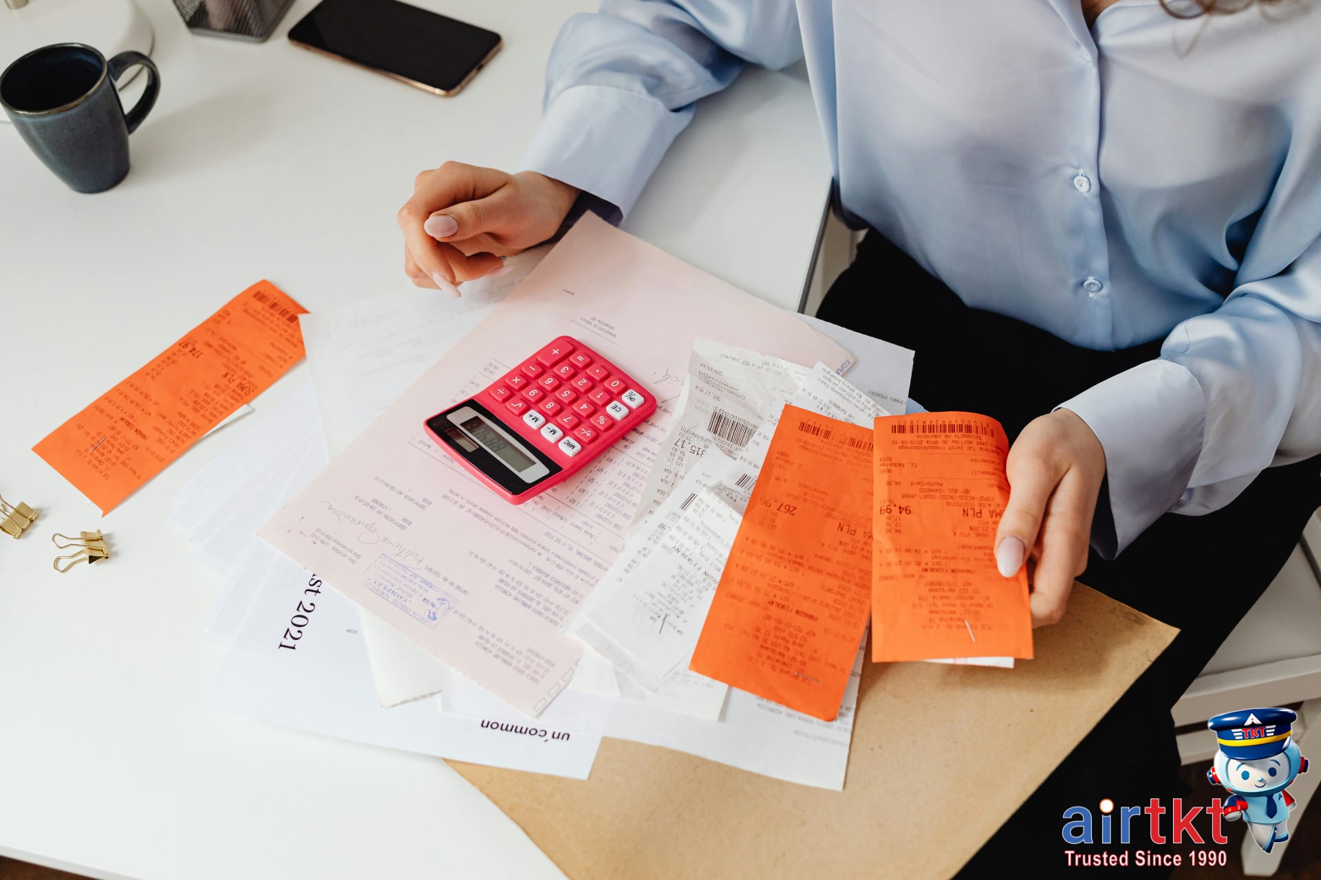 Hands calculating travel insurance claim reimbursement with receipts at a desk