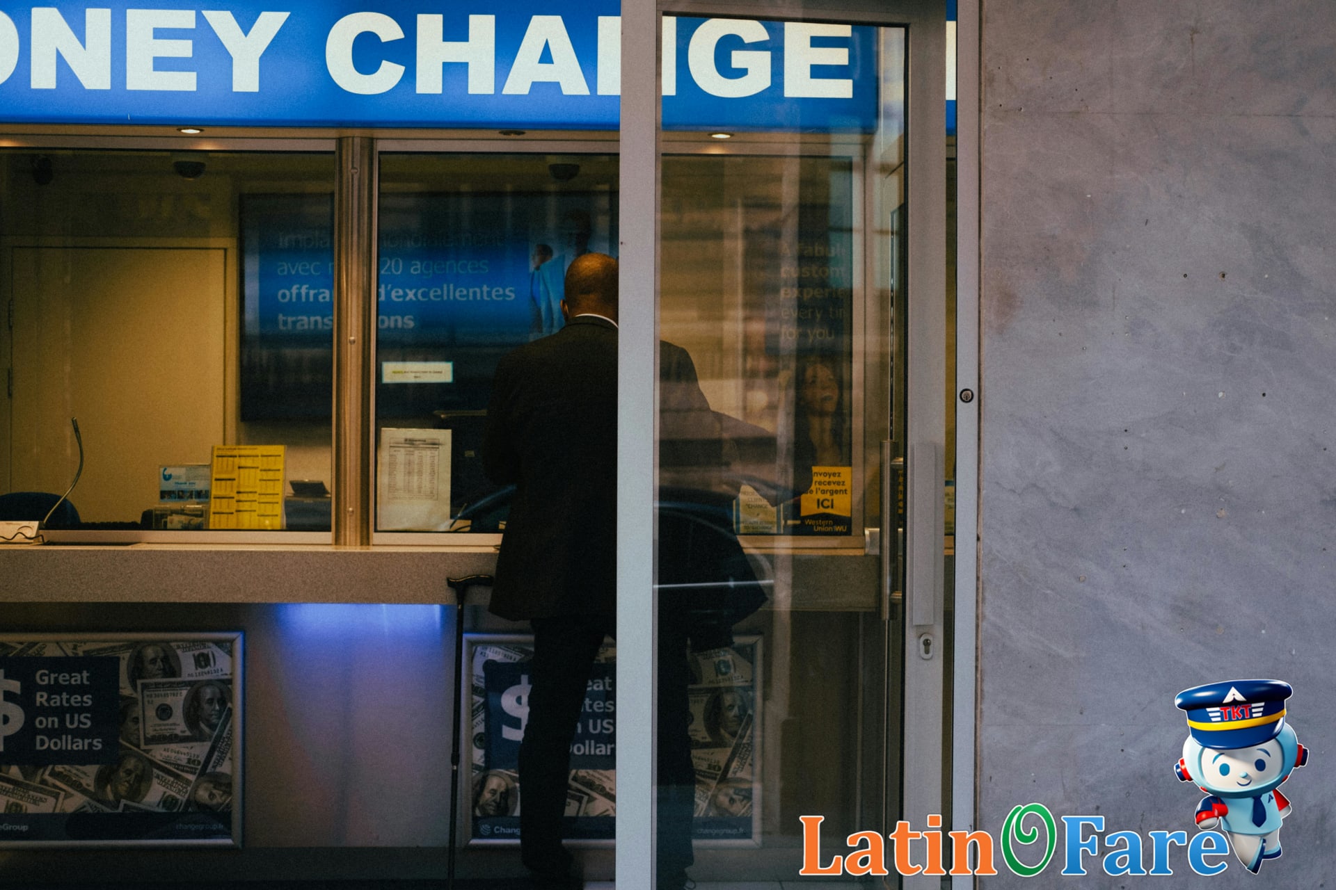 Man at airport exchanging currency checking posted exchange rates at kiosk