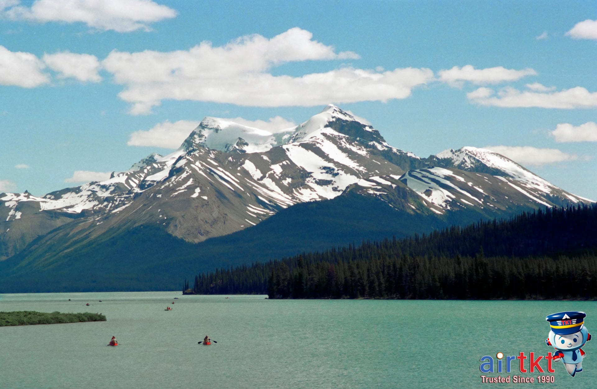 Maligne Lake with boat and surrounding forested peaks in Jasper National Park