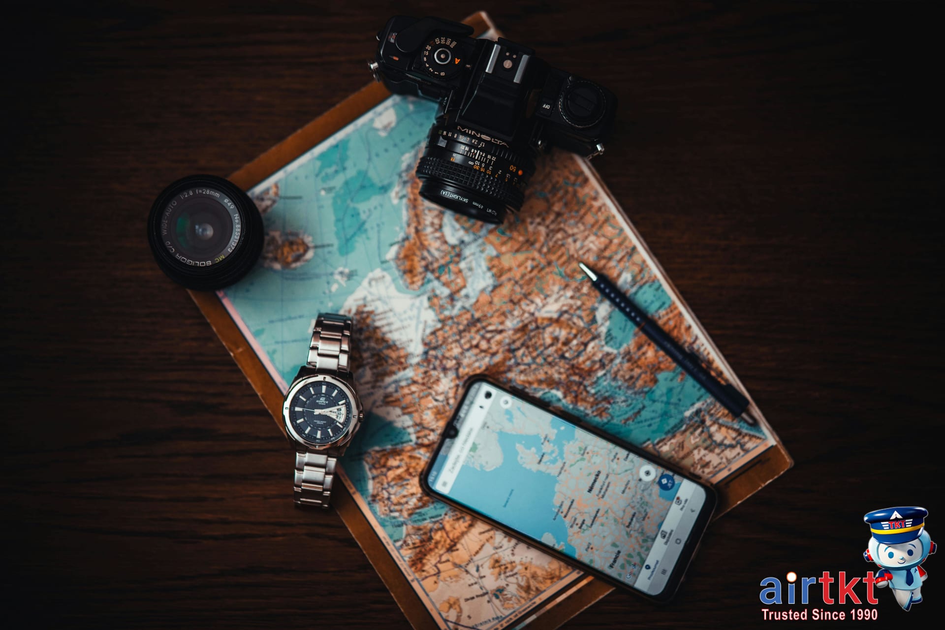 Travel essentials including map camera and phone laid out for itinerary planning