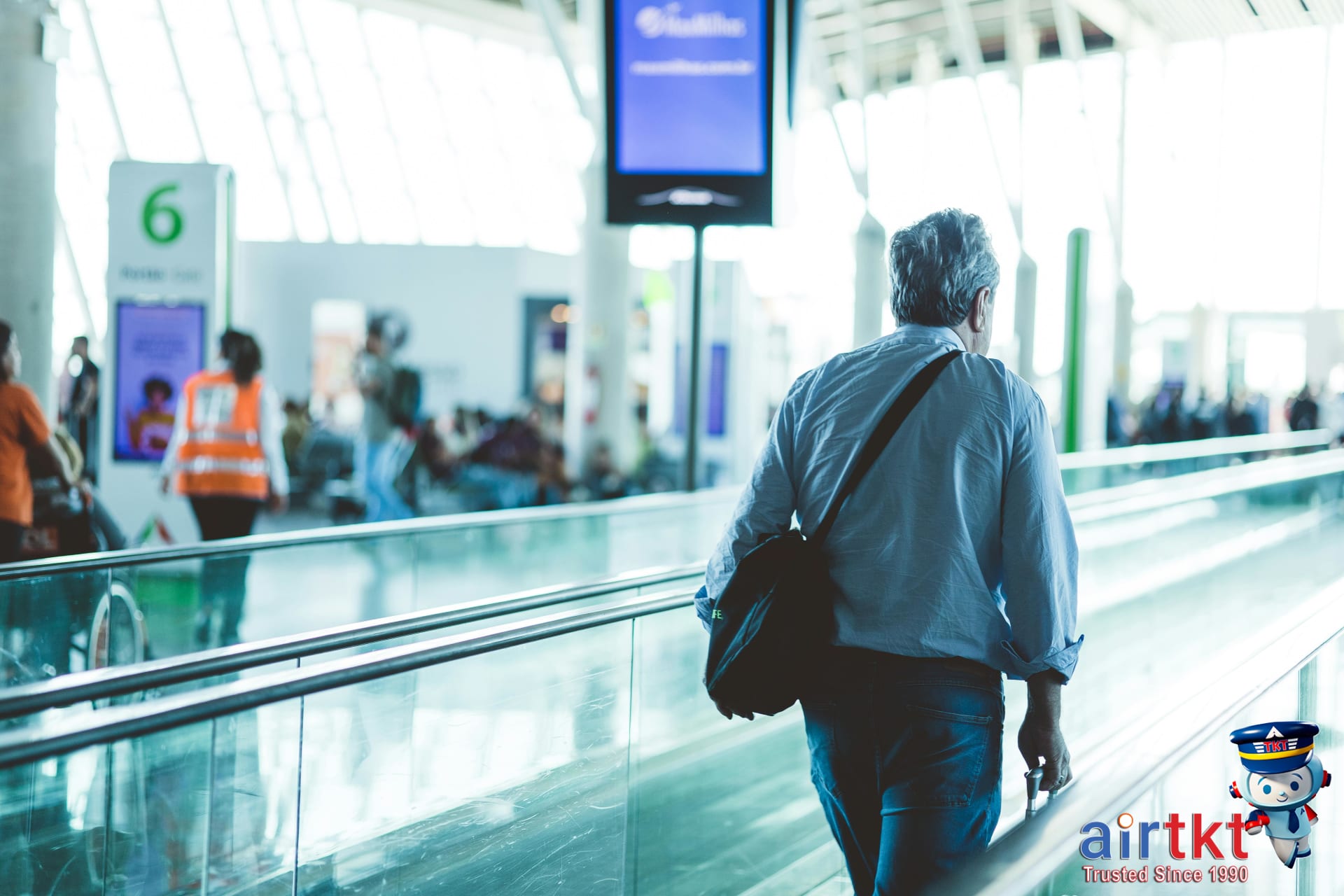 Traveler carrying luggage on airport travelator walking towards check-in