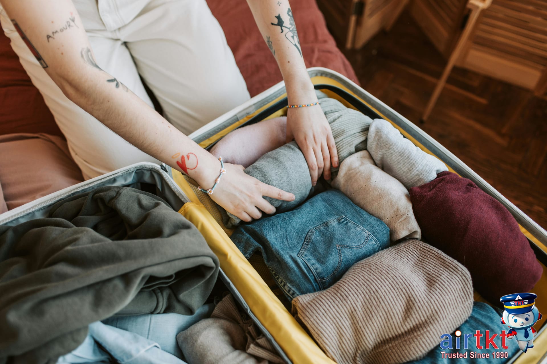 Person packing clothes efficiently into suitcase for smart travel preparation