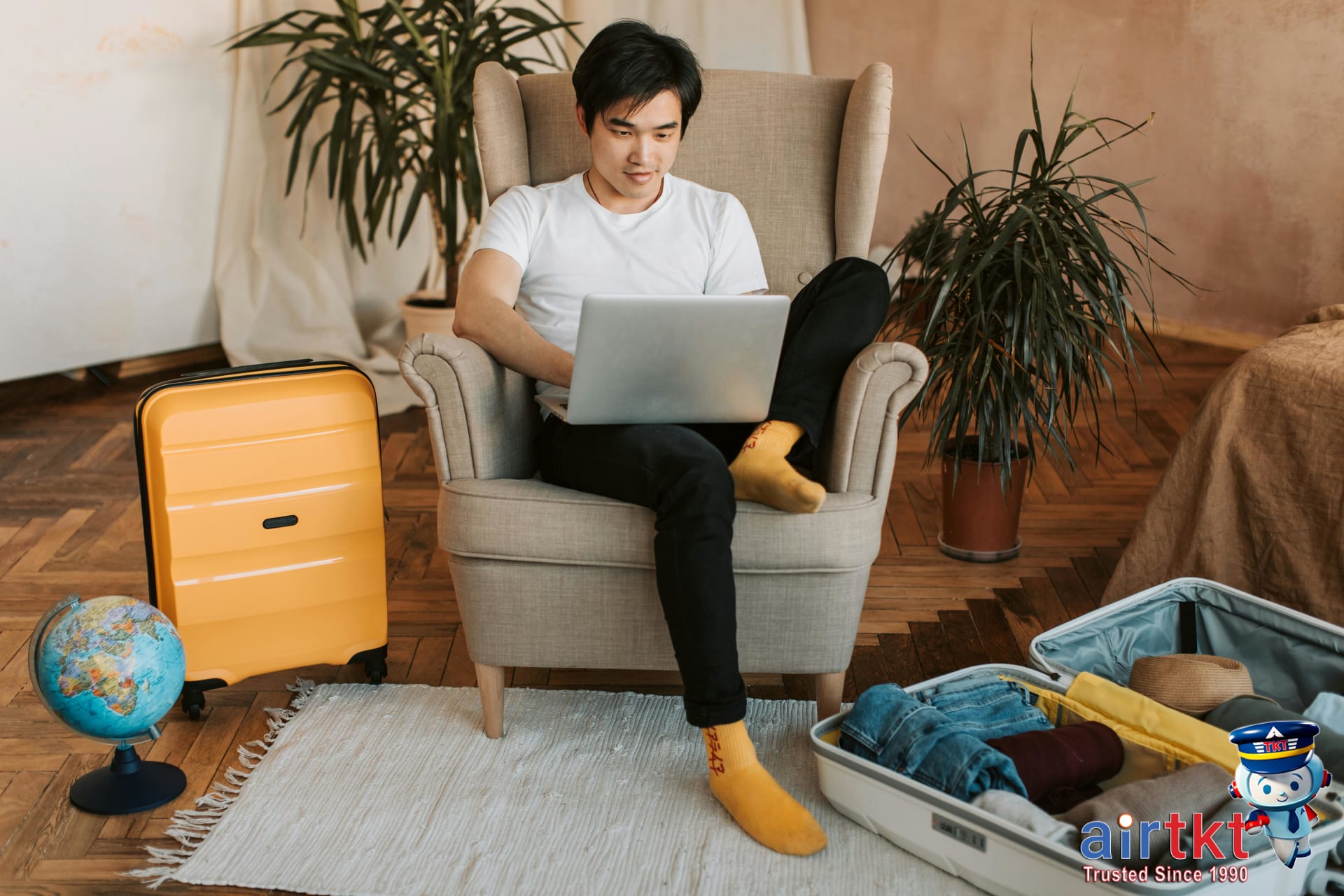 Man researching travel destinations using laptop and globe beside him for planning