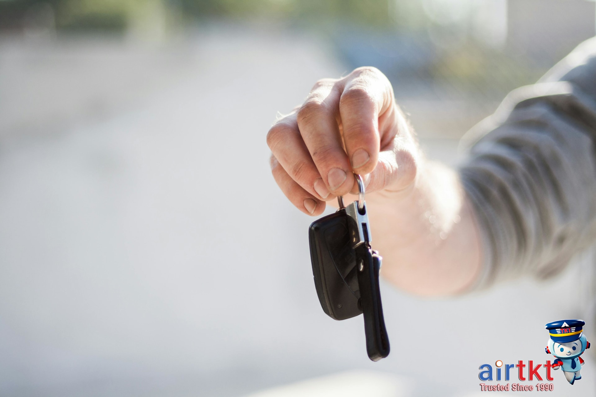 Close-up of hand handing over car keys highlighting budget rental booking tips for young drivers