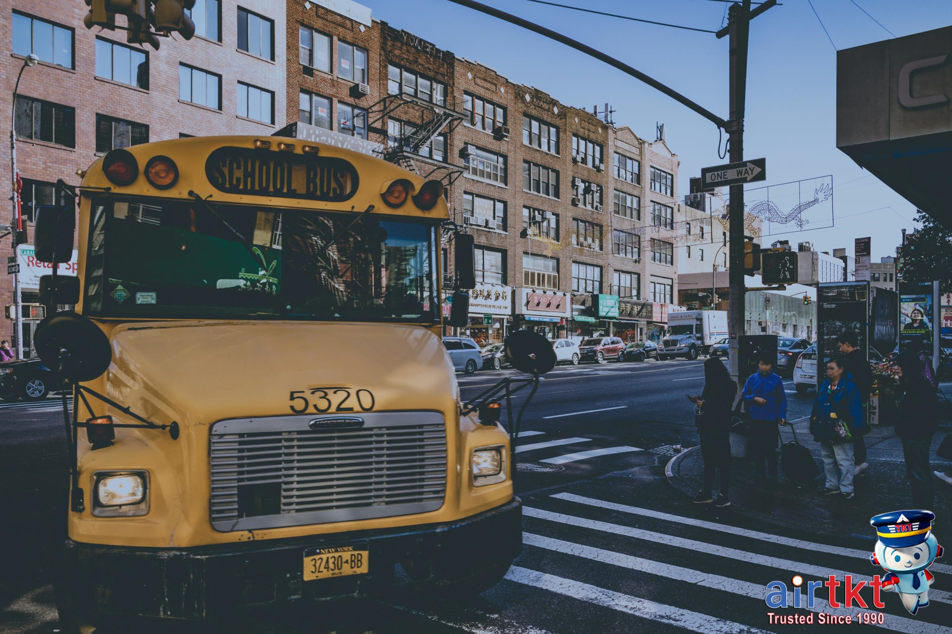 Yellow NYC bus with passengers boarding on a busy city street during daylight hours