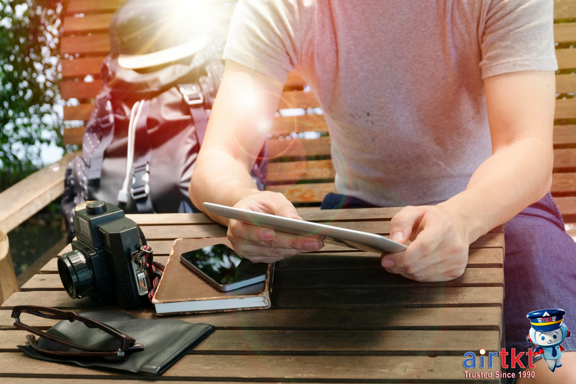 Traveler exploring mistake fare FAQ on tablet in outdoor park setting