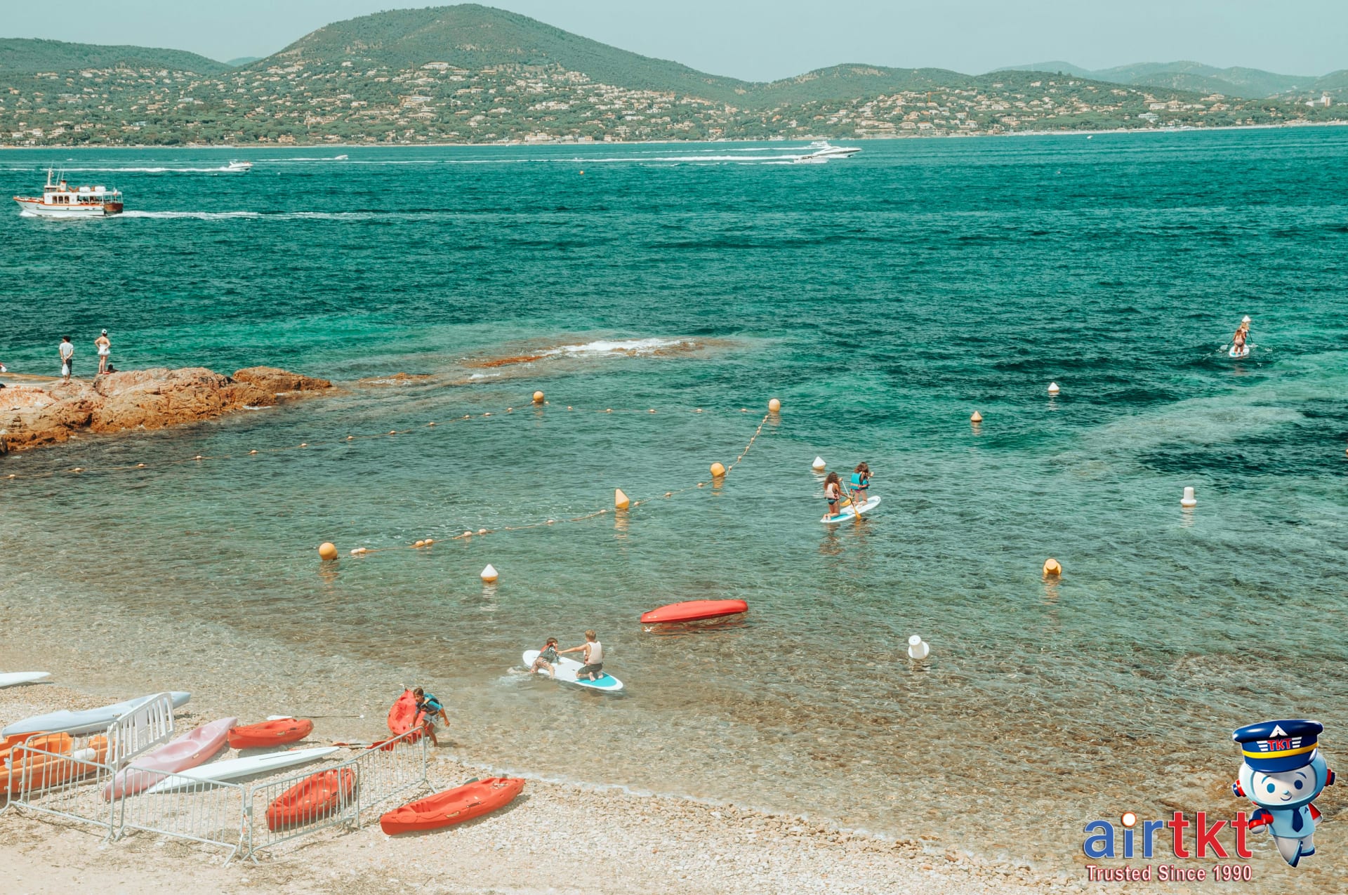 People kayaking and paddleboarding on Mediterranean waters under a sunny sky