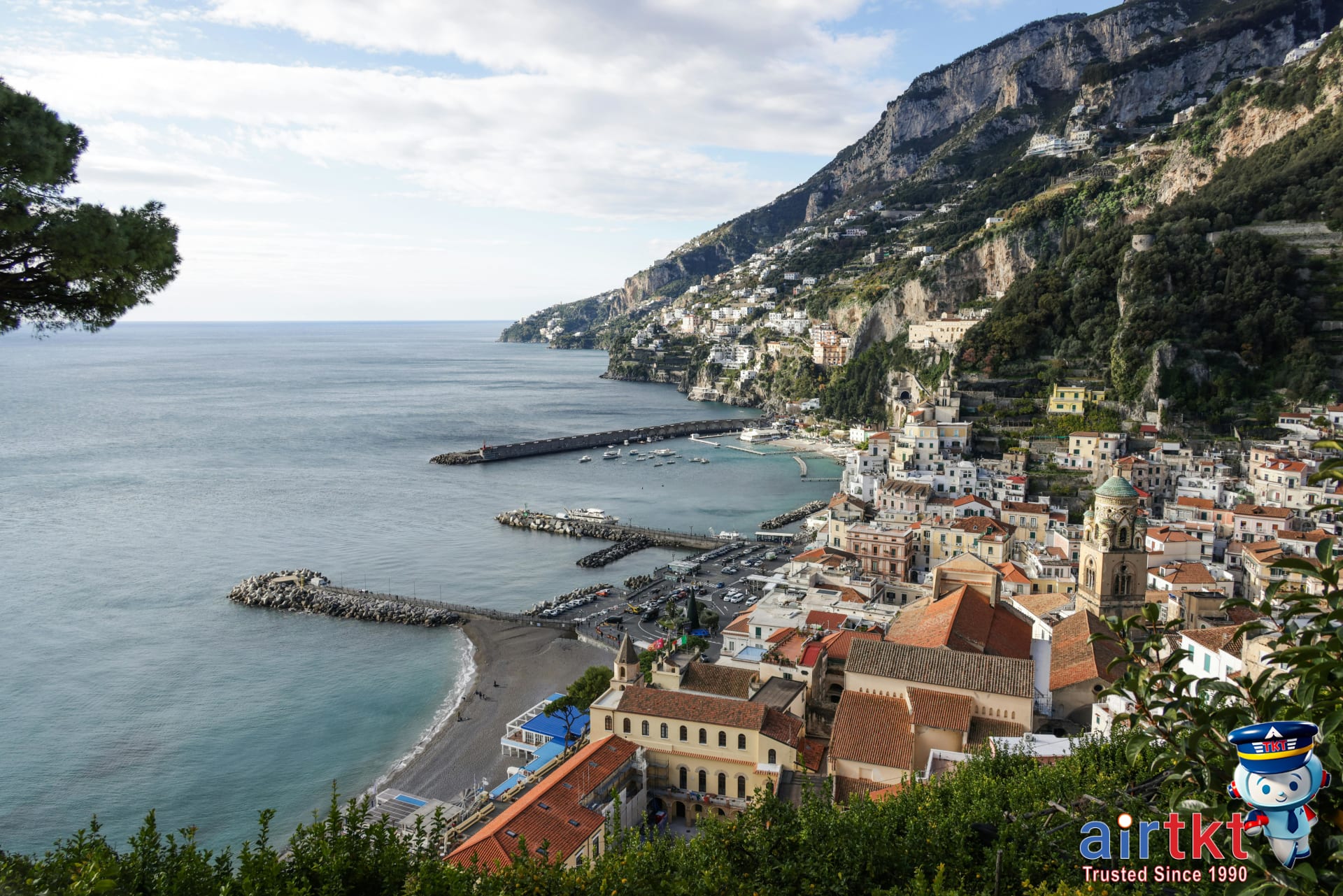 Amalfi Coast beach with dramatic cliffs, colorful houses, and blue sea under clear skies