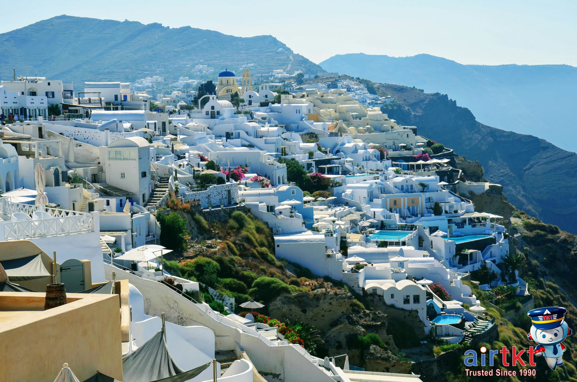 Greek Isles beach with white houses and blue domes facing turquoise sea