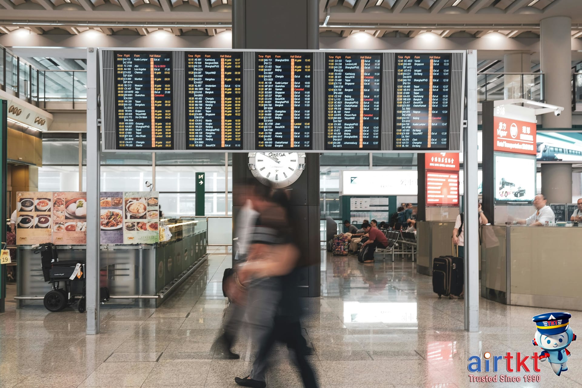 Airline passengers waiting amid delay notice on flight display in airport lounge
