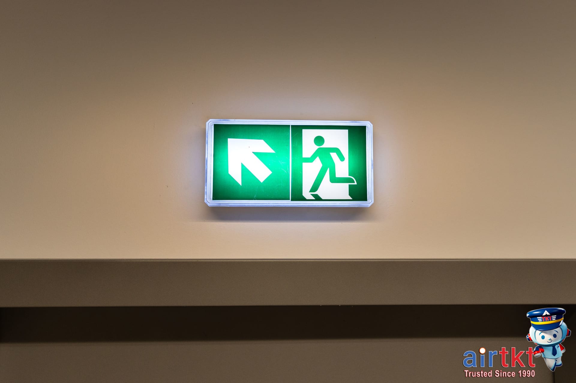 Hotel hallway showing emergency exit signs and preparedness kit on luggage cart