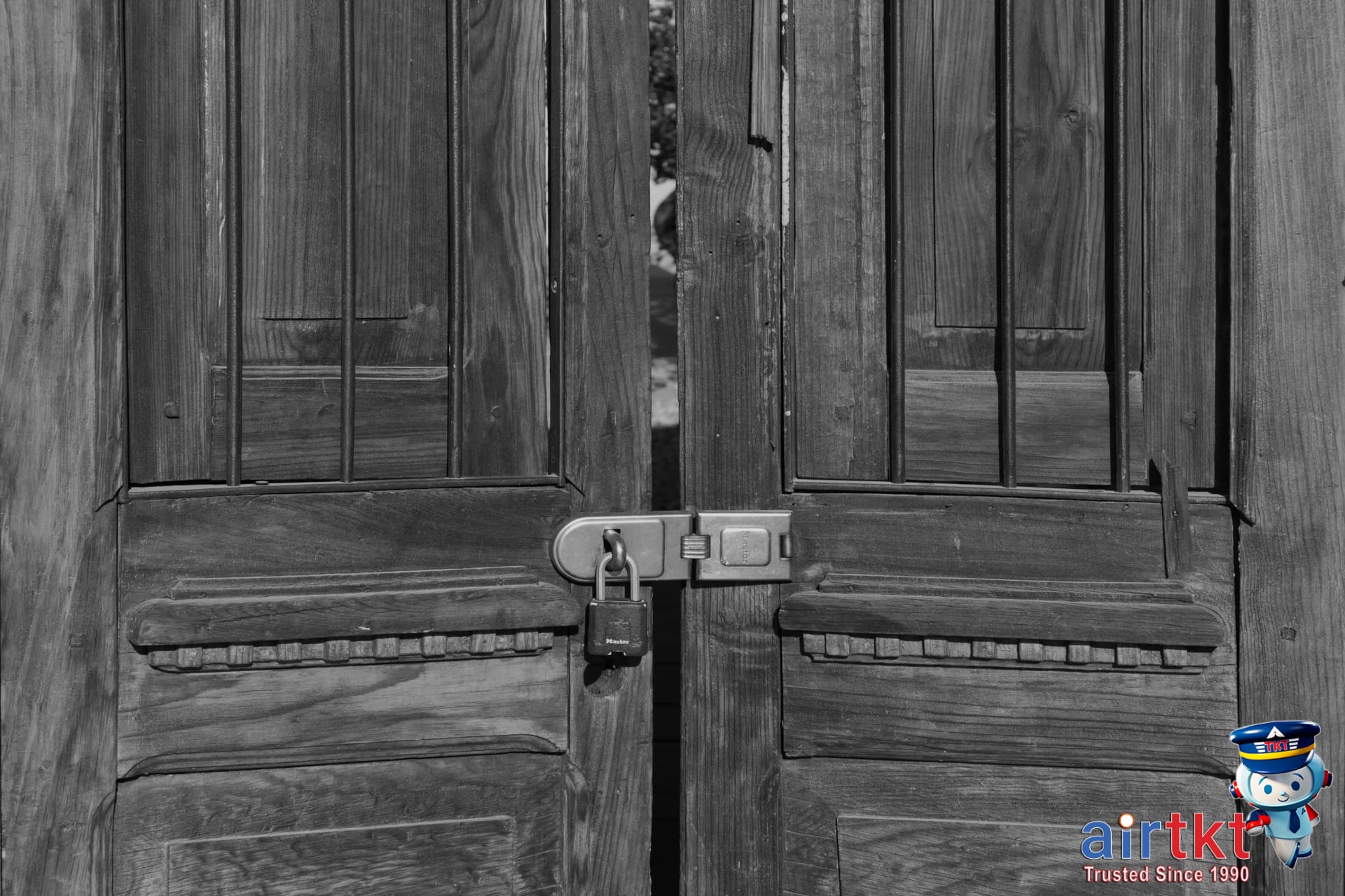 Wooden hotel door secured with black iron bars and padlock for hotel room security