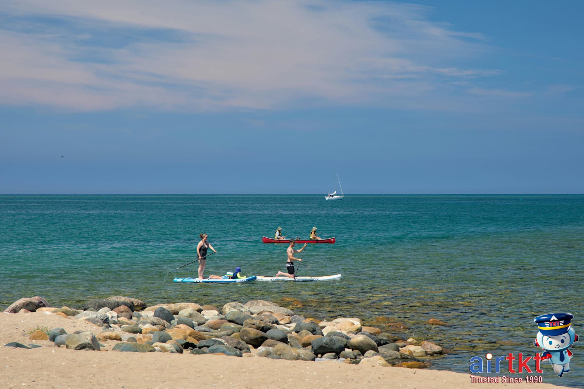 People kayaking and paddle boarding off Cape Cod rocky shoreline