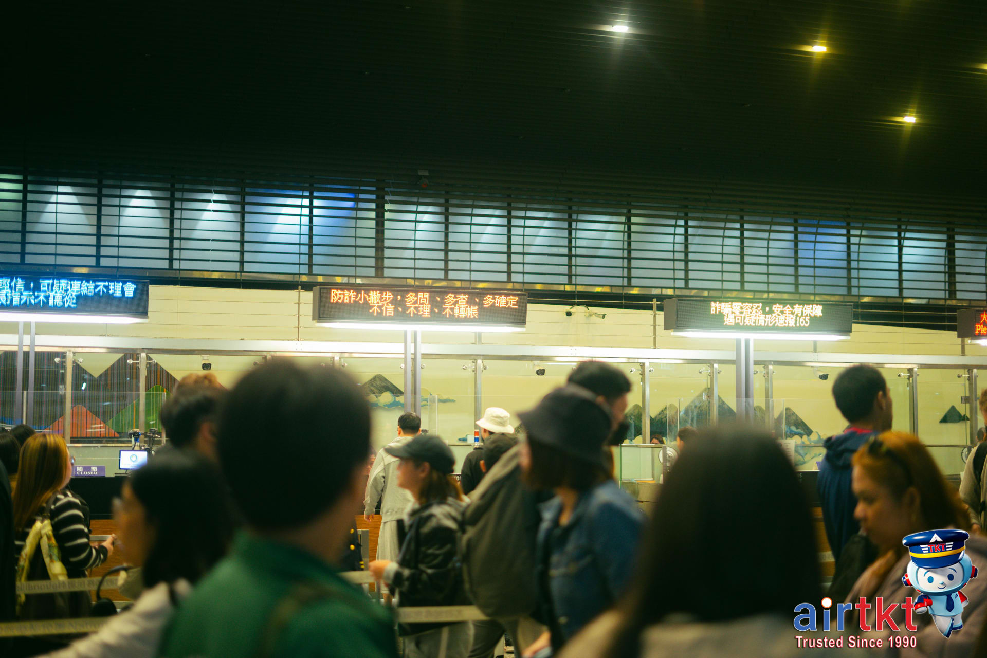 Crowded airport check-in area with upgrade signage and passengers in queue