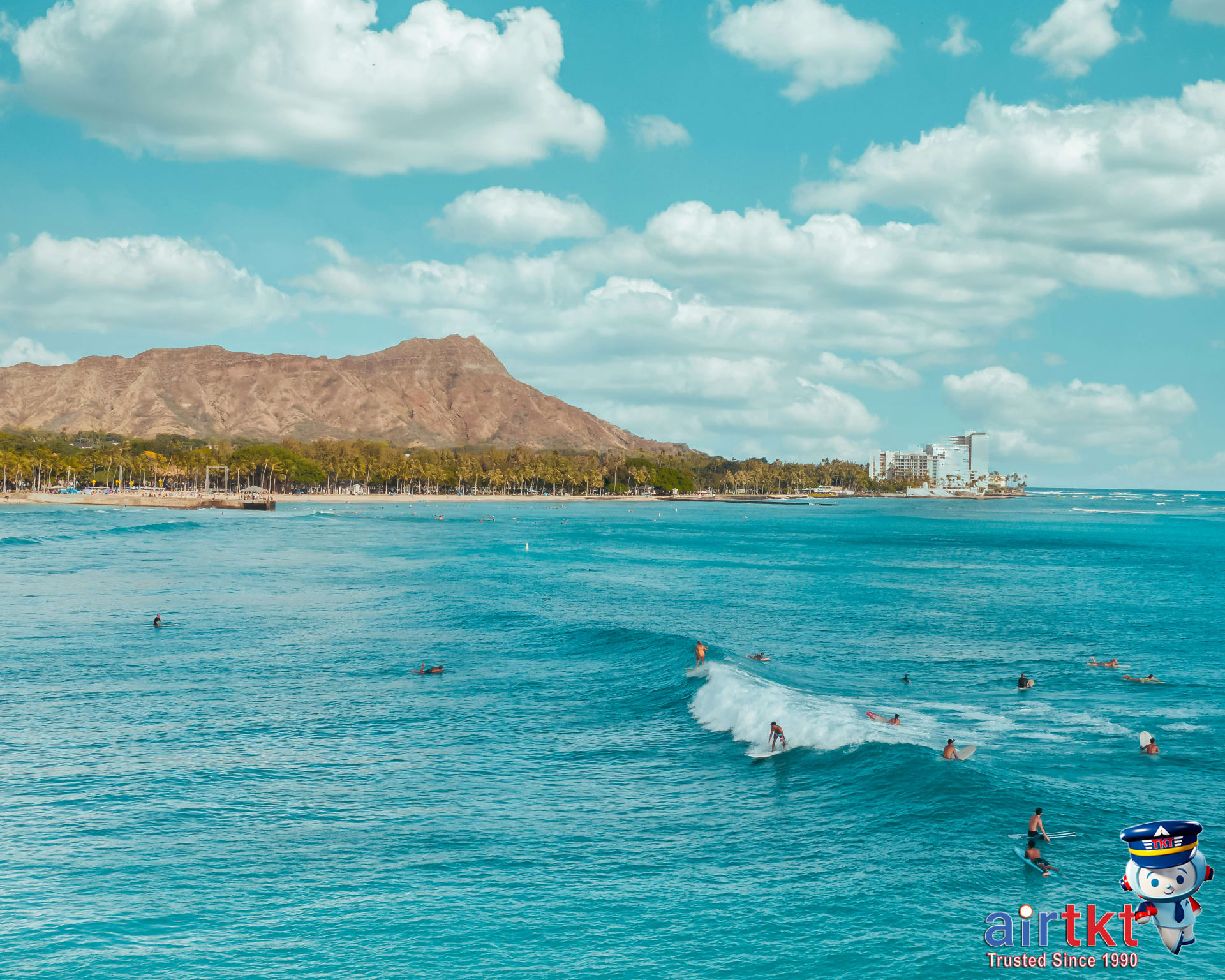Surfers enjoying waves at Waikiki Beach with Diamond Head in the background