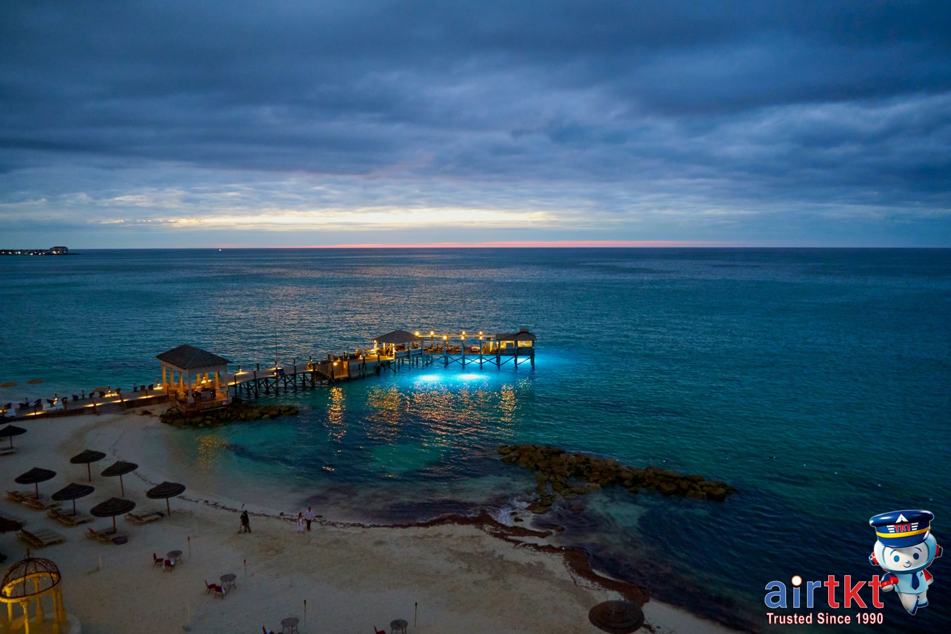 Sunset over tranquil Bahamas beach with calm ocean.