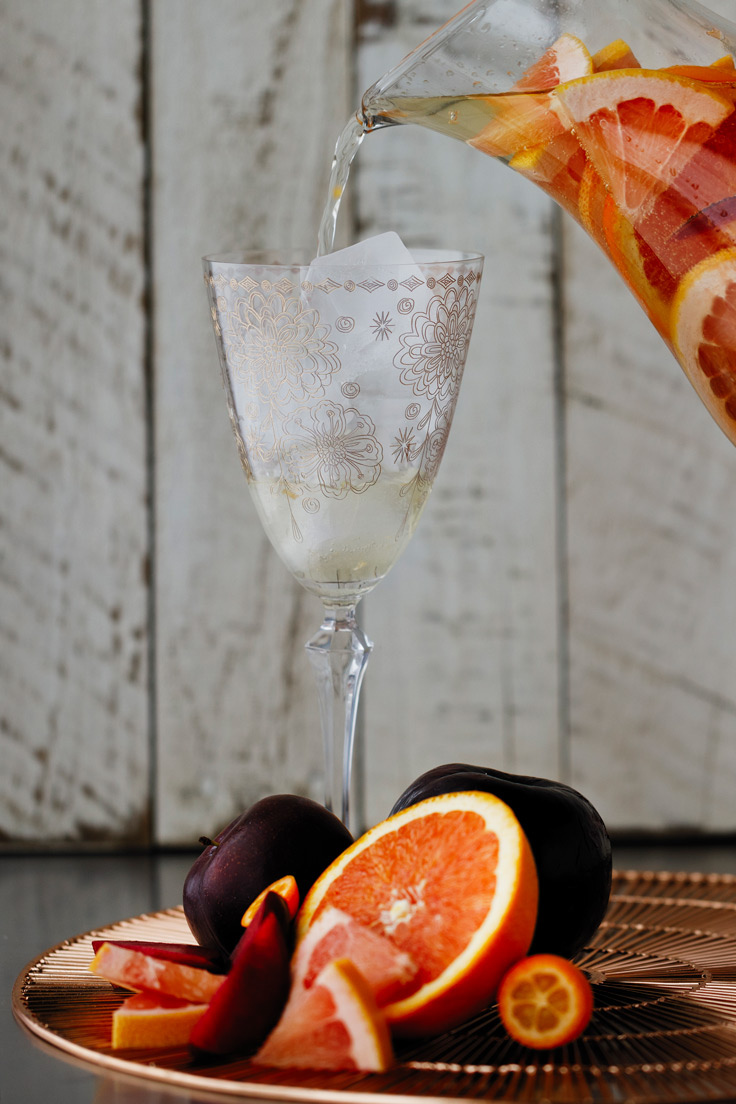 Pour a glass of Amoretti Summer Sangria Recipe with stone fruits and citrus