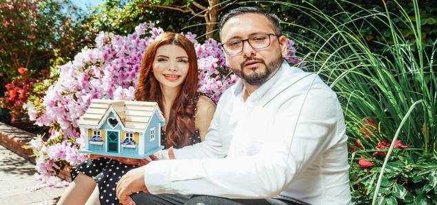 A man and woman showing a miniature house toy