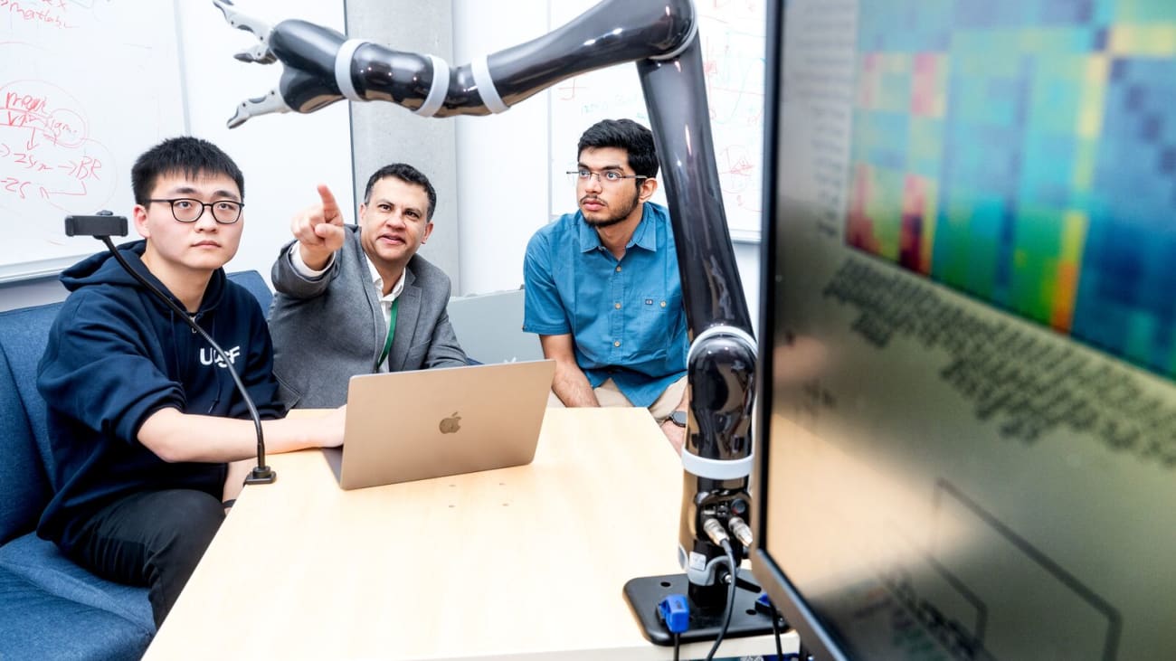robotic arm Karunesh Ganguly, MD, PhD (center), works in his lab with graduate students Runfeng Miao (left) and Harsha Peesapati (right). Photo by Noah Berger