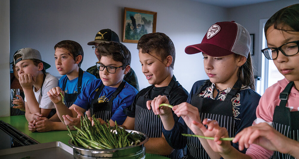 Canadian First Nations children in a kitchen trying asparagus