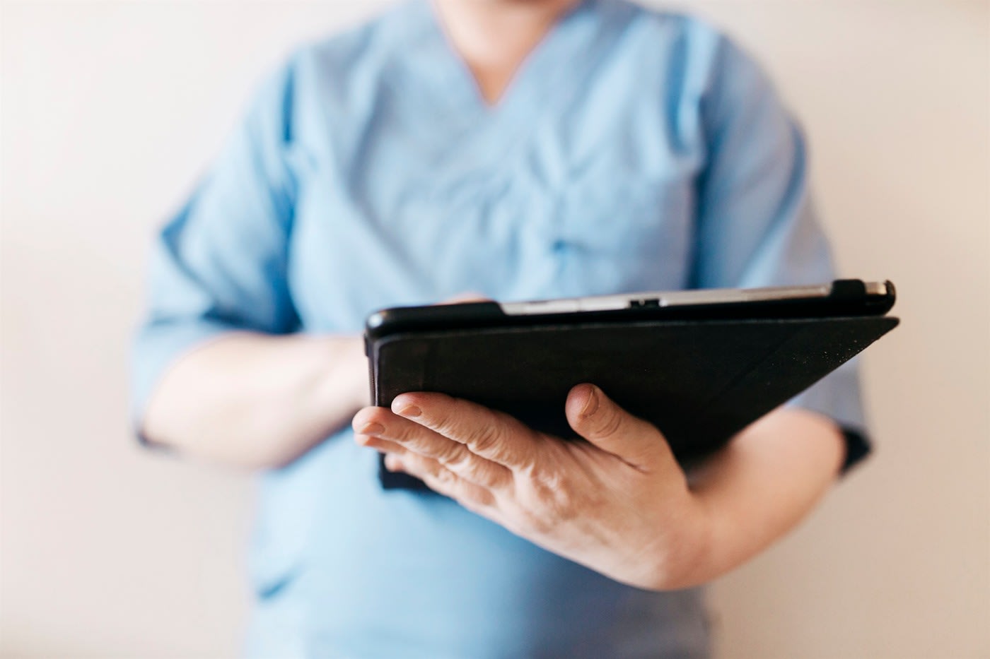 sjukvårdspersonal med blå arbetskläder håller i en lasplatta