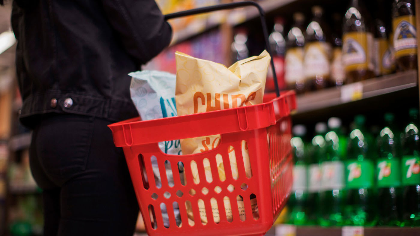 En person står med en varukorg fylld med chips